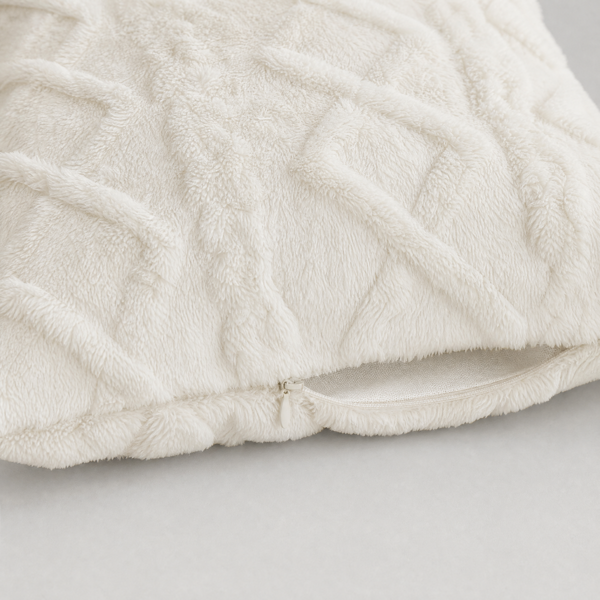 Hidden zipper along the bottom seam of the cream cable knit cover