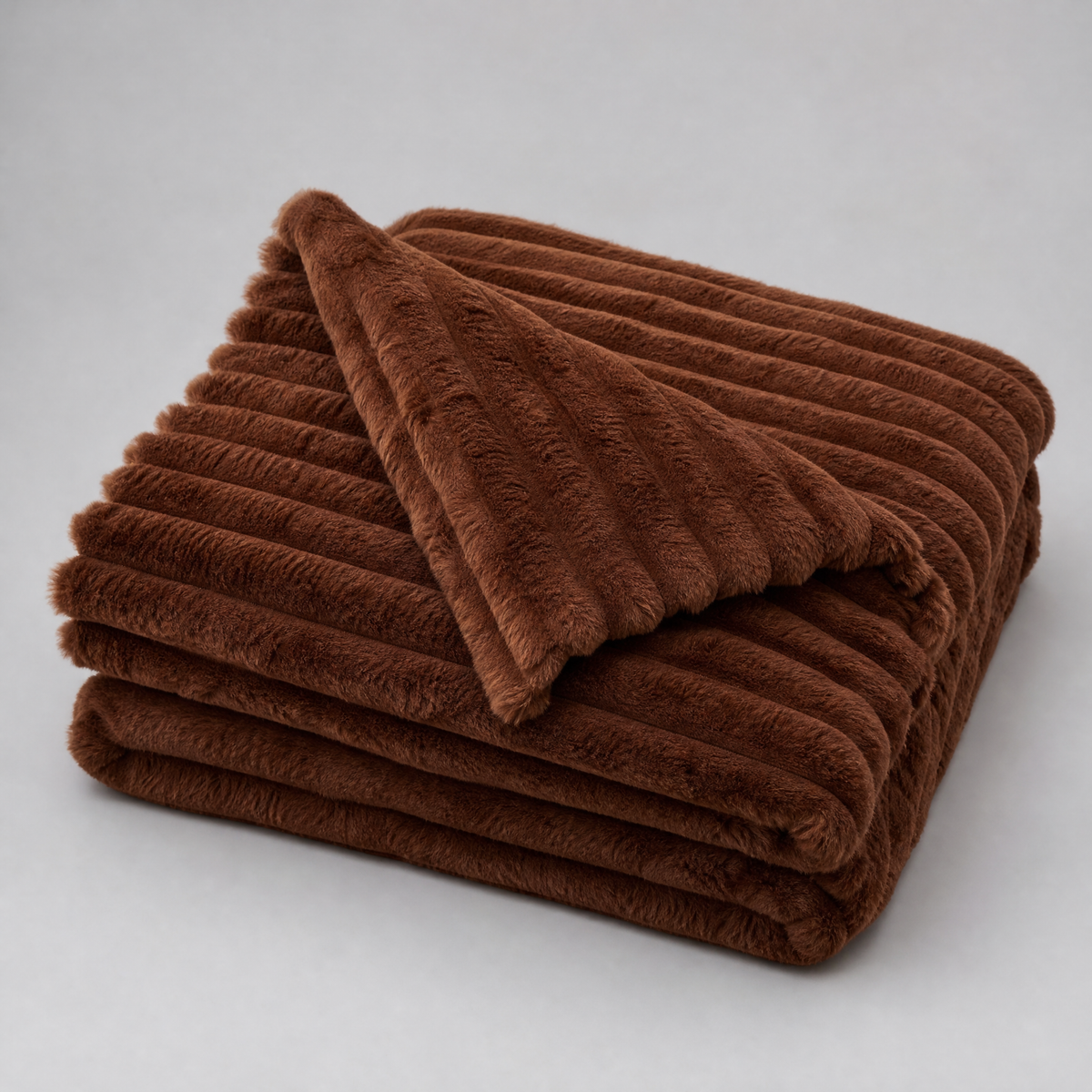 Brown chunky ribbed faux fur couch cover, folded, on a light grey background
