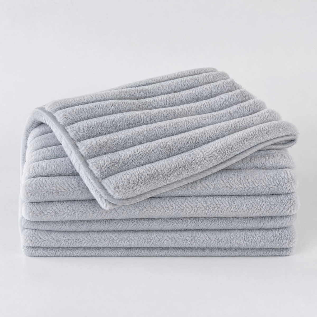 Light Grey chunky ribbed faux fur couch cover, folded, on a light grey background