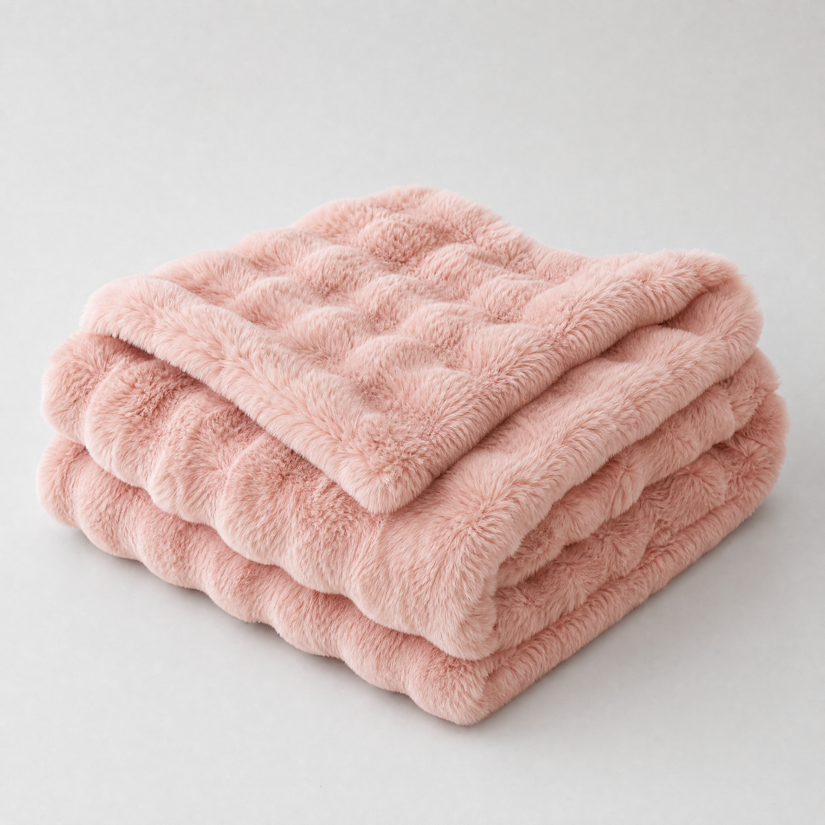 Pink faux rabbit fur couch cover, folded, on a light grey background