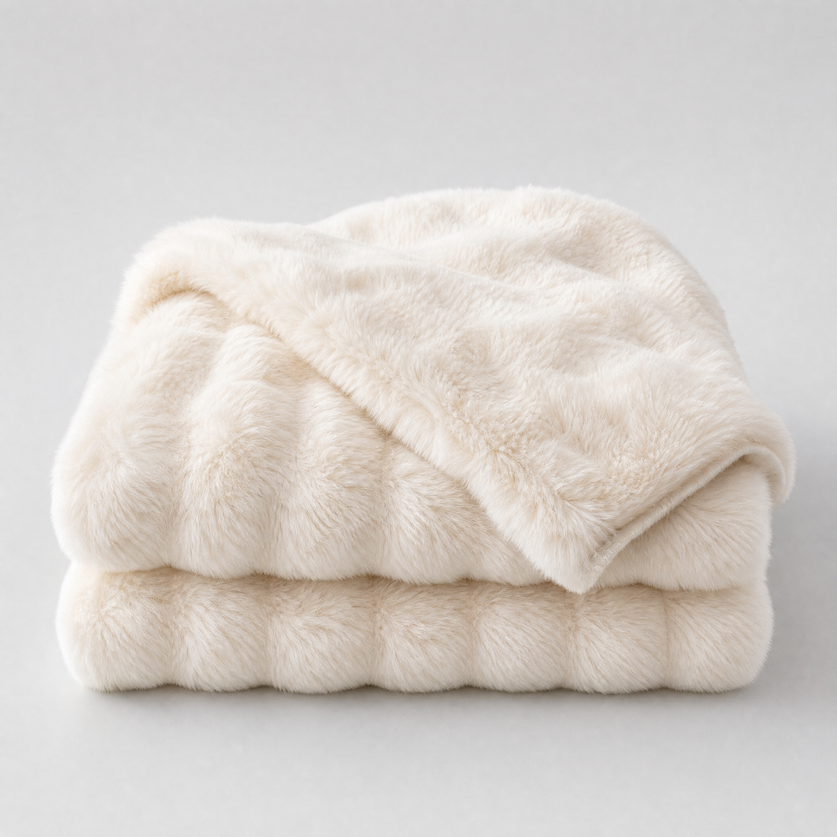 White faux rabbit fur couch cover, folded, on a light grey background