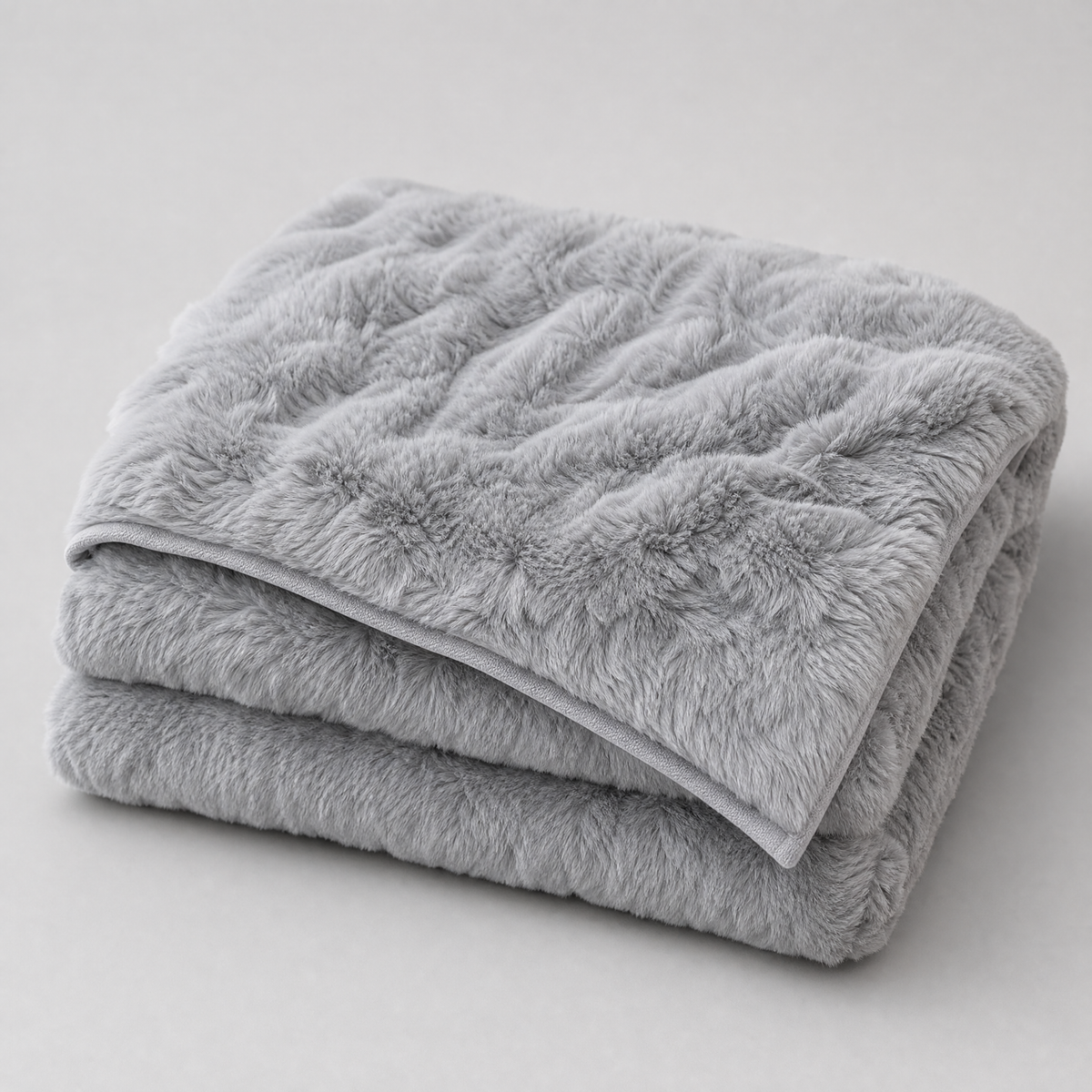 Light Grey faux rabbit fur couch cover, folded, on a light grey background