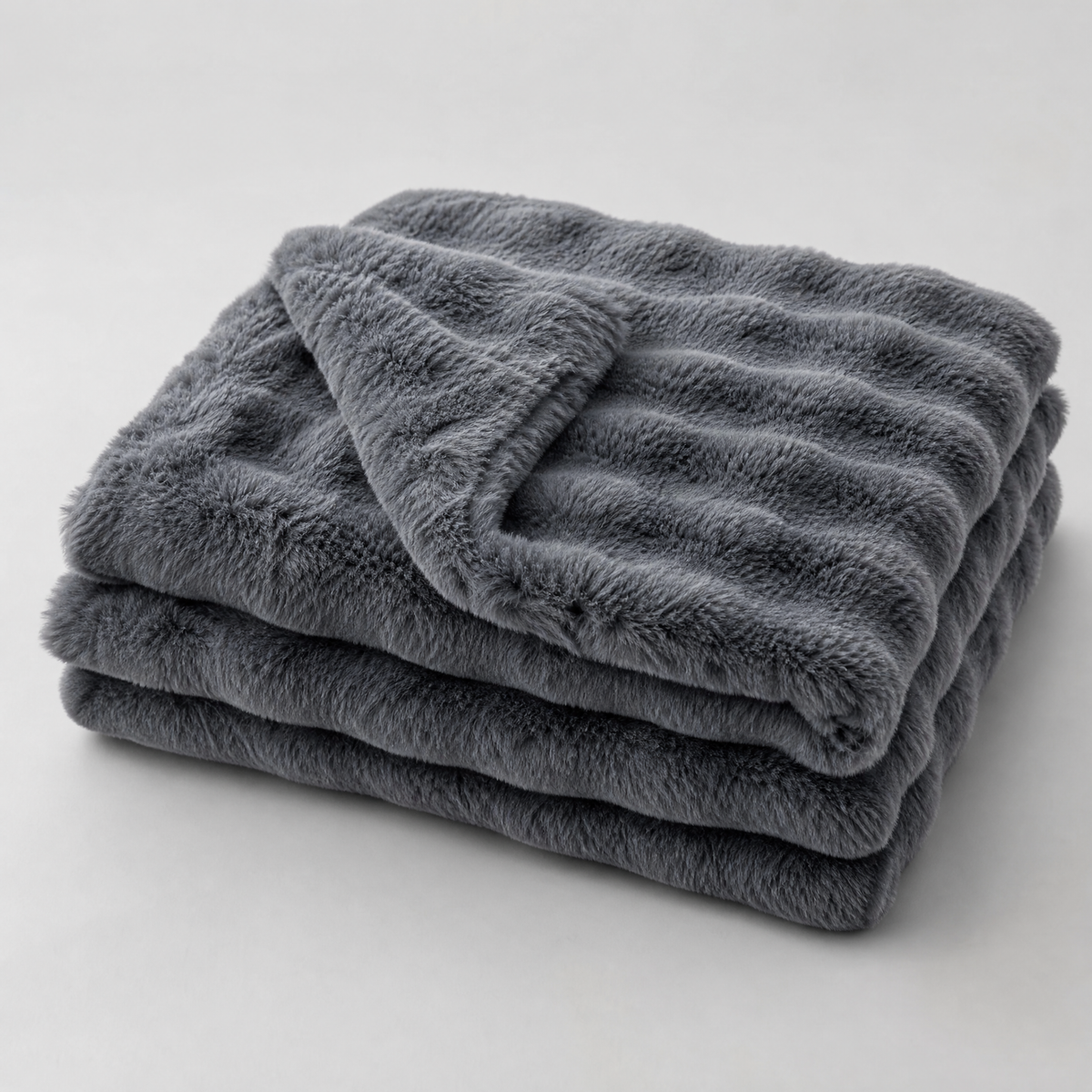 Dark Grey faux rabbit fur couch cover, folded, on a light grey background