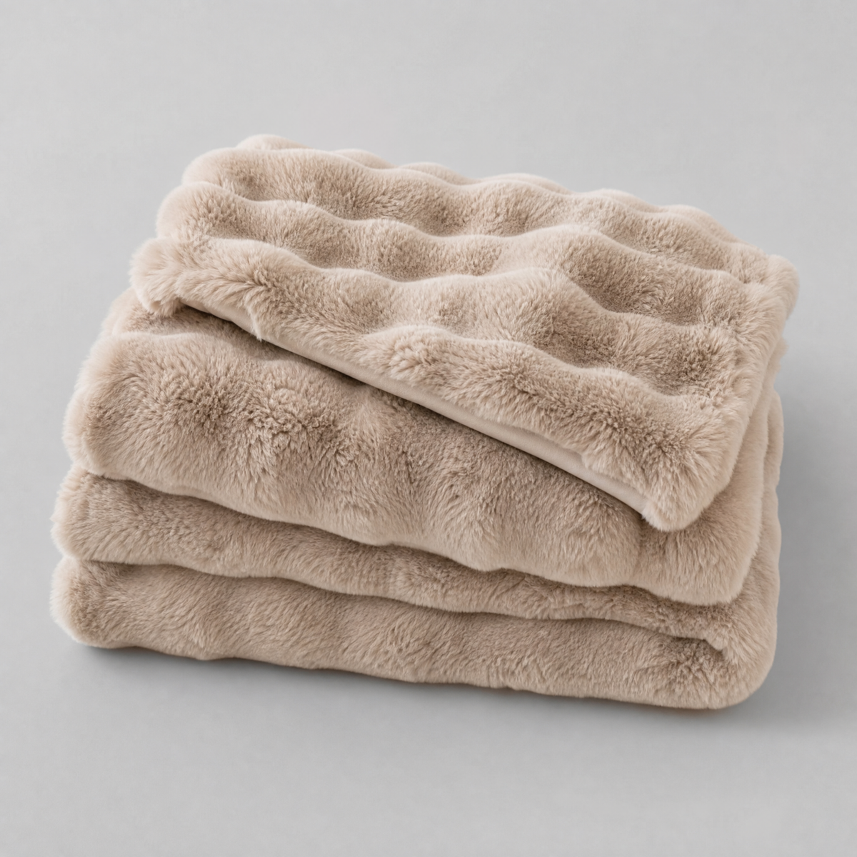 Khaki faux rabbit fur couch cover, folded, on a light grey background