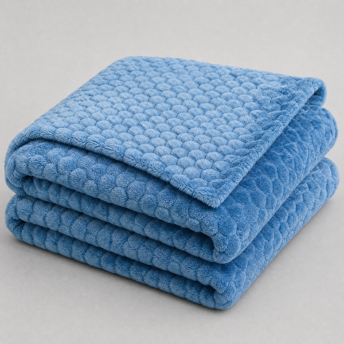 Royal Blue honeycomb velvet couch cover, folded, on a light grey background