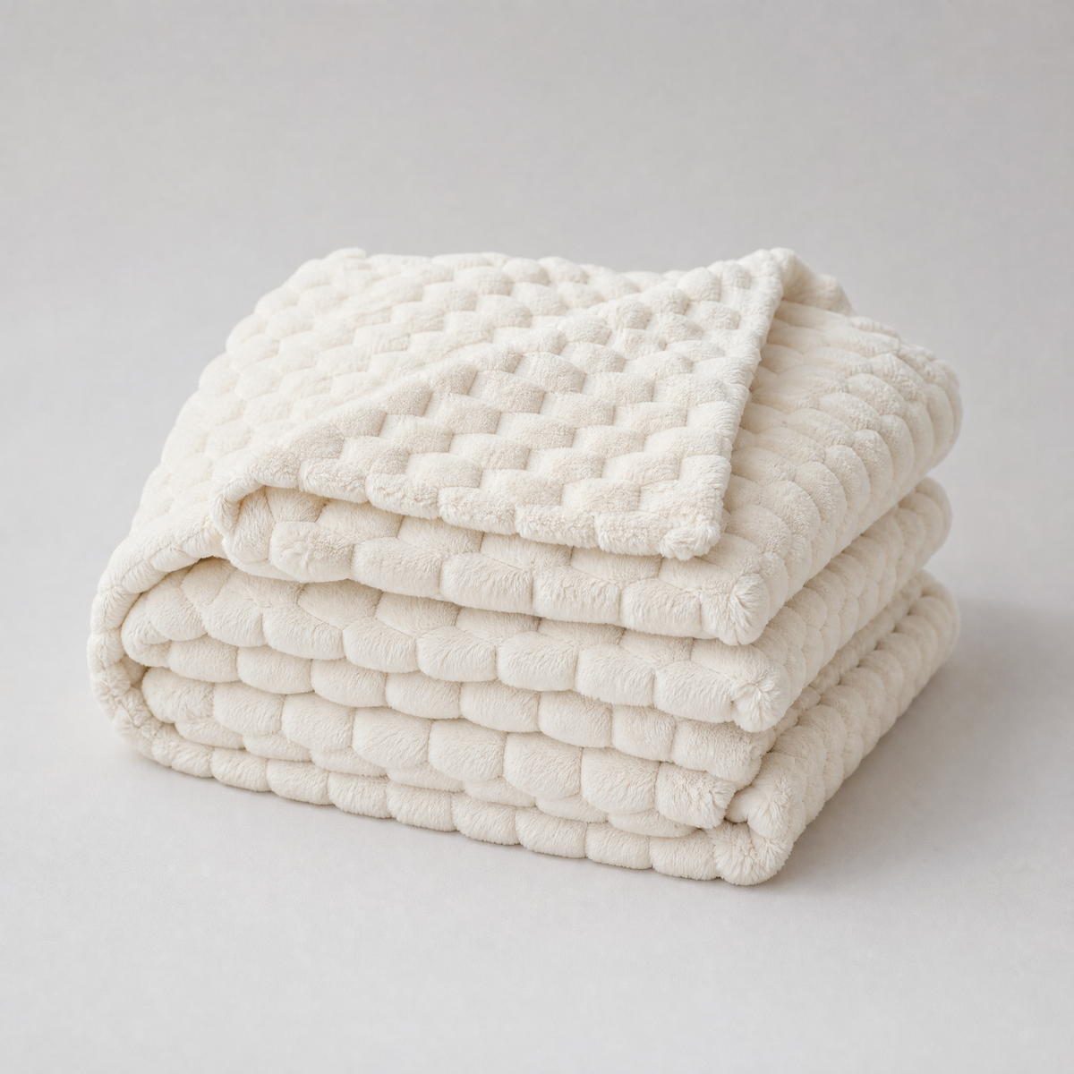 Milk White honeycomb velvet couch cover, folded, on a light grey background