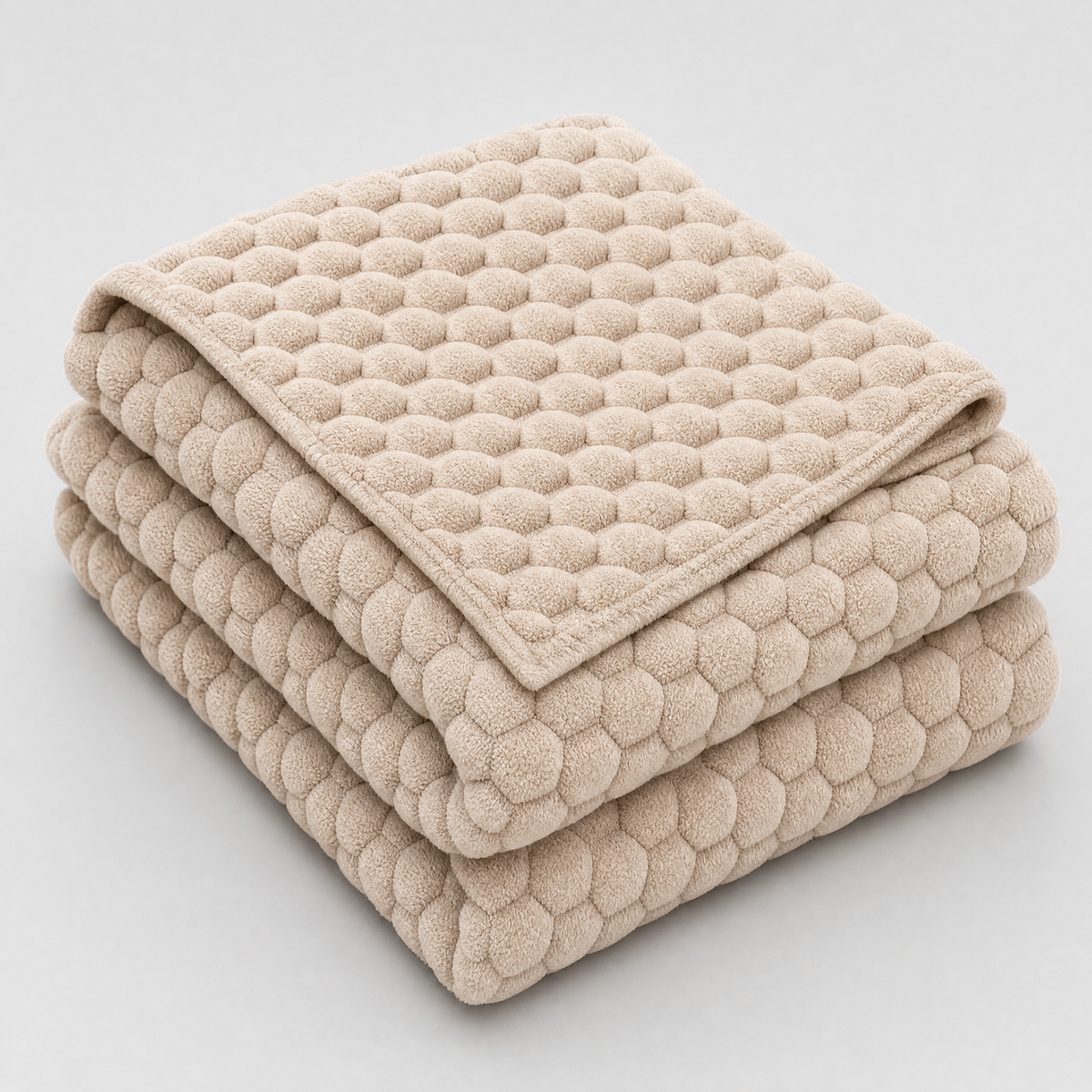 Latte honeycomb velvet couch cover, folded, on a light grey background