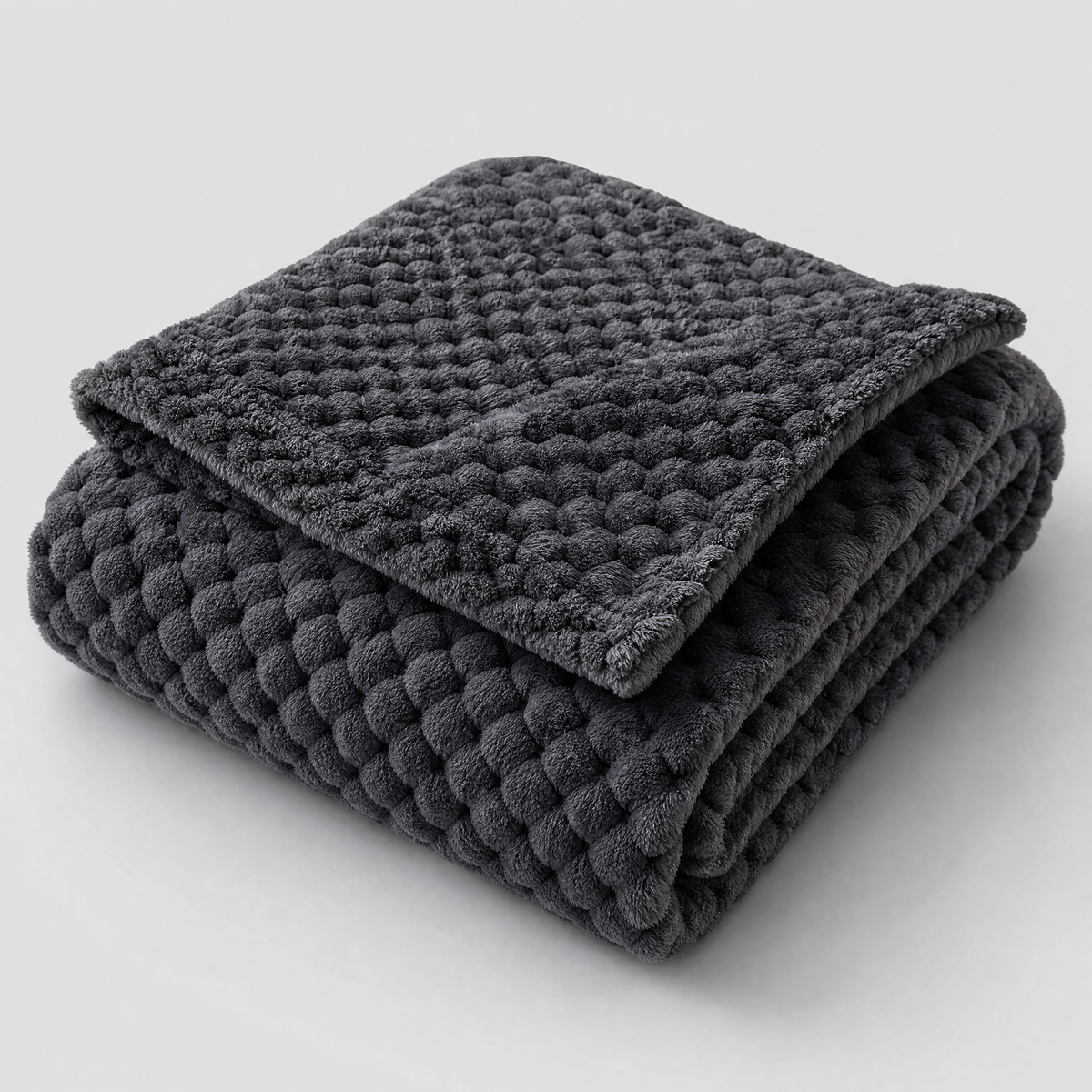 Charcoal honeycomb velvet couch cover, folded, on a light grey background
