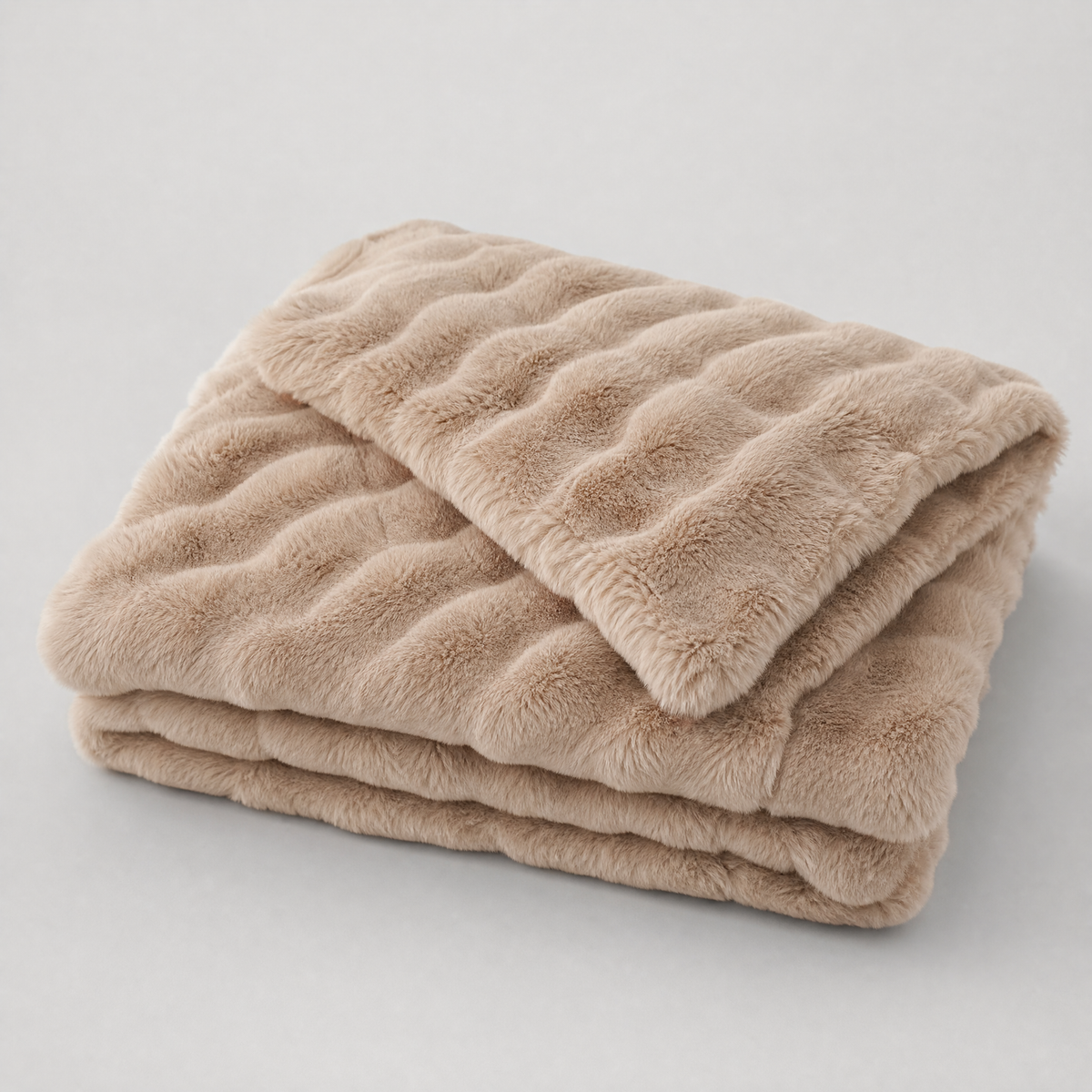 Taupe quilted faux fur couch cover, folded, on a light grey background