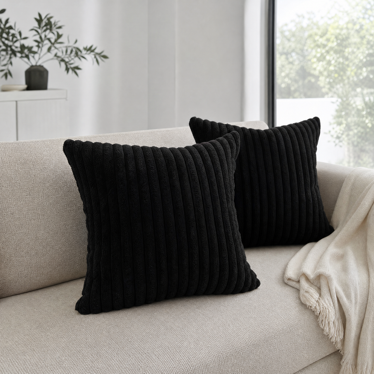Black plush cushions on a linen sofa seen from a low angle showing their depth