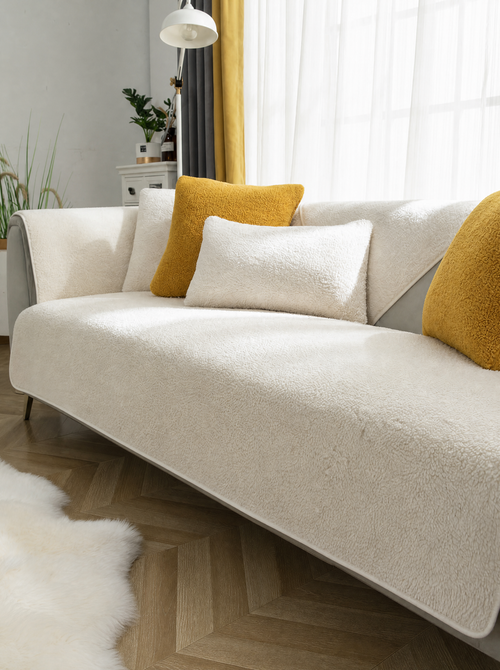 White sherpa couch cover on a sofa in a bright living room