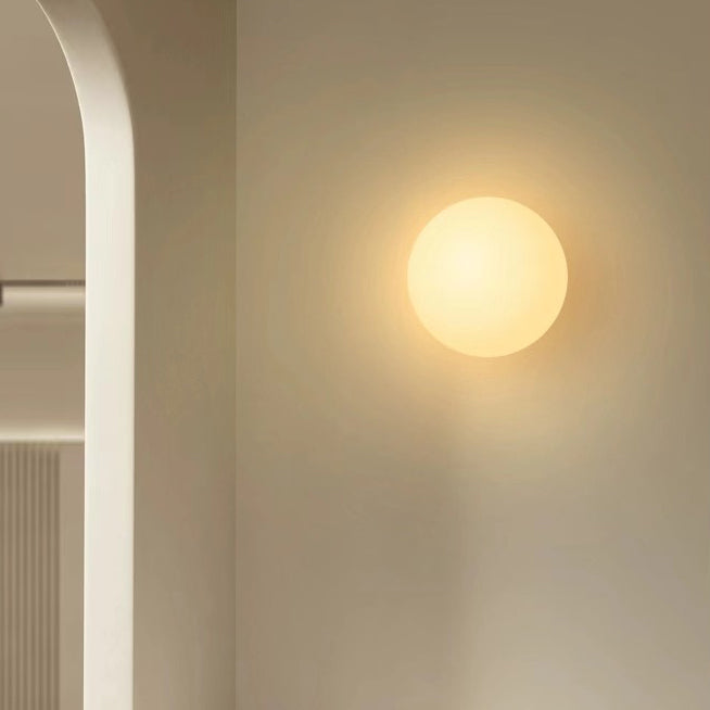 Frosted glass orb wall sconce switched on beside a doorway