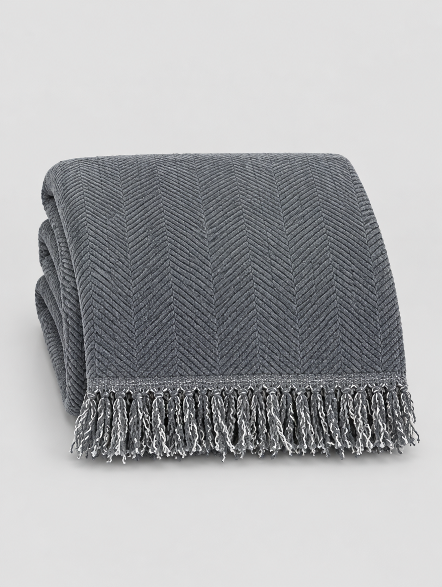 Tassel Couch Cover Throw in grey, folded on a light grey background