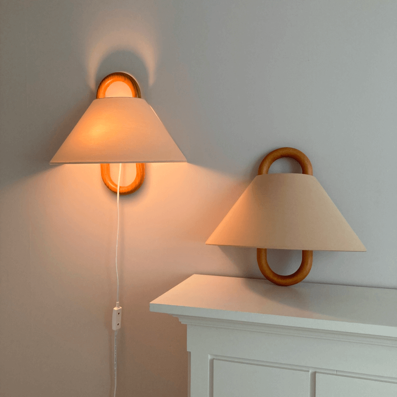 Wood loop wall sconce with fabric shade above a bed