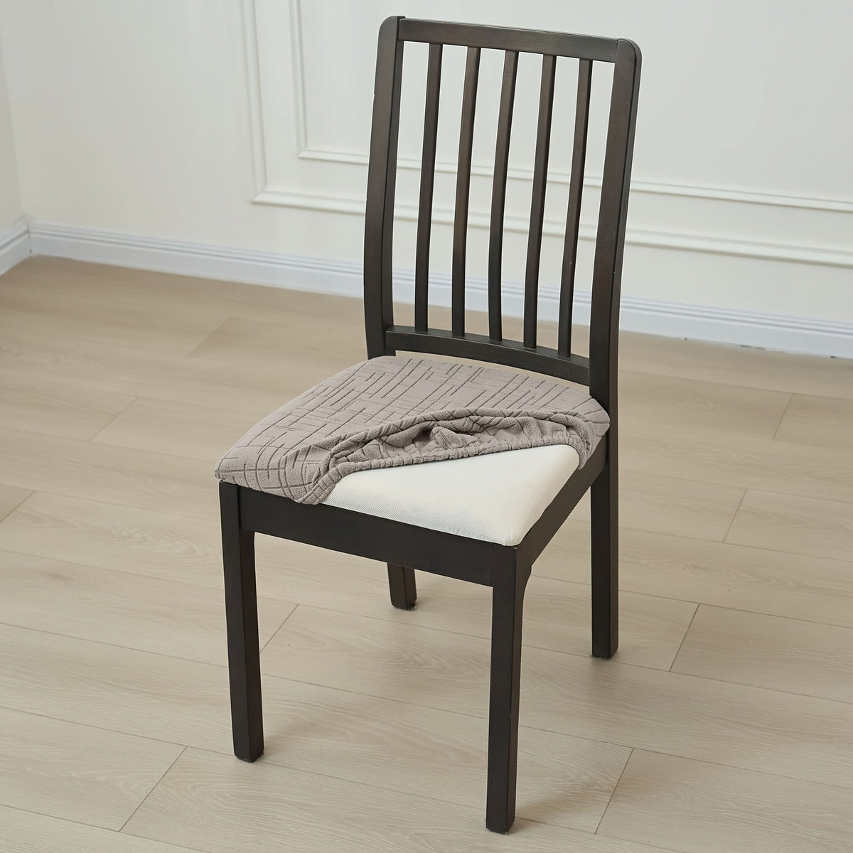 Stretch seat cover being pulled over a dining chair seat